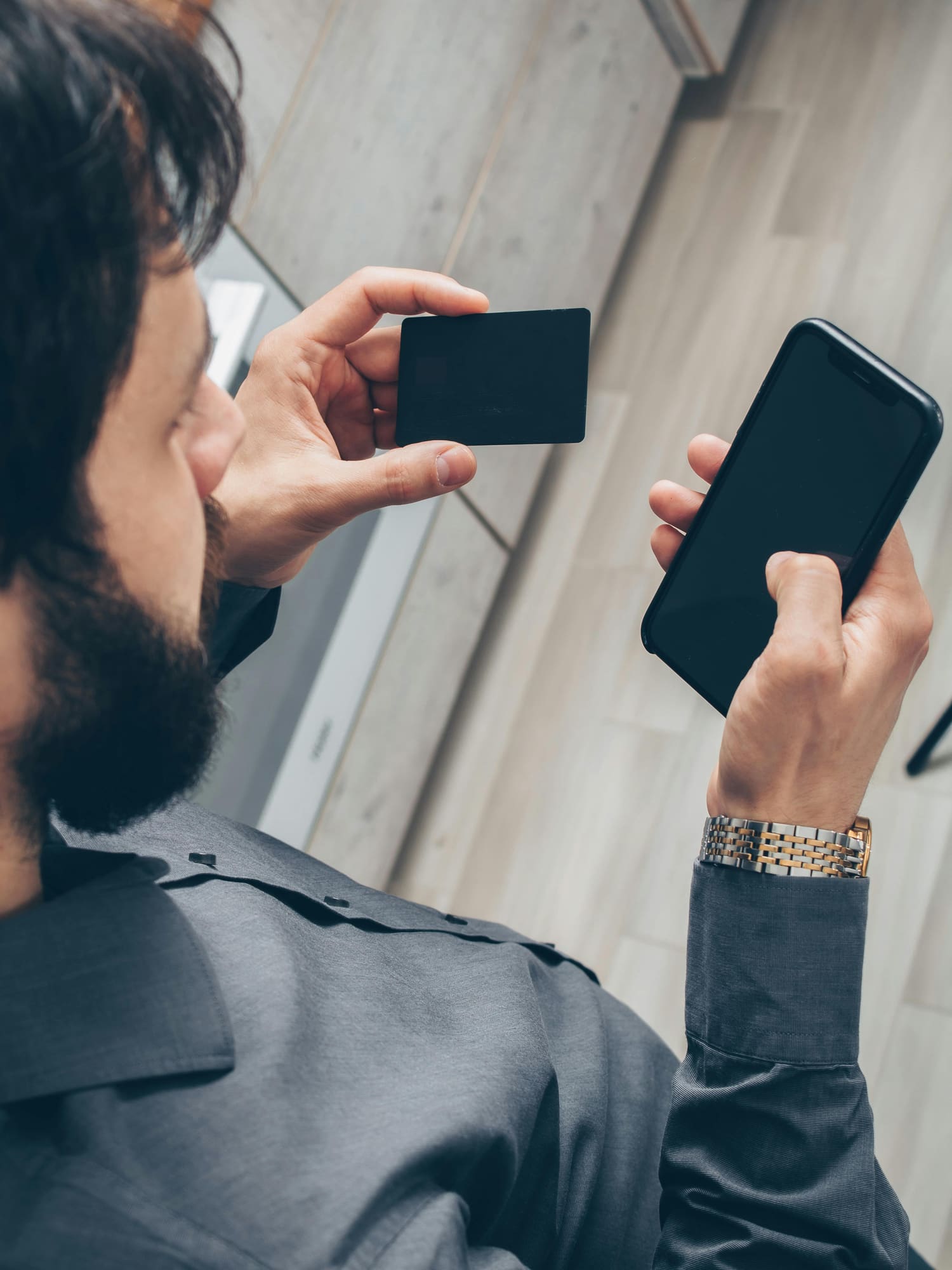 Hands holding a phone and a card, ready to tap
